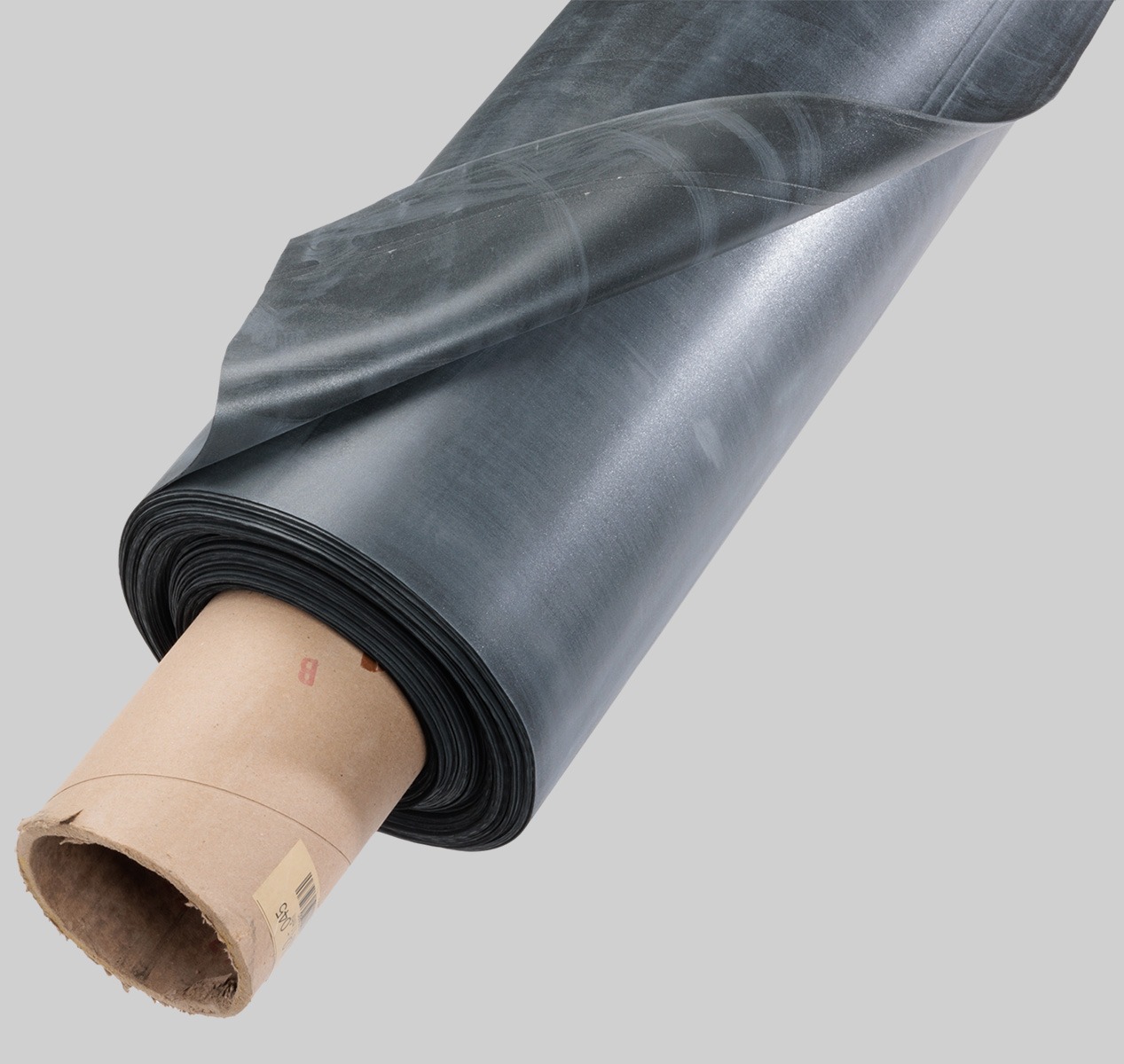 A large roll of black plastic sheet is partially unrolled, wrapped around a brown cardboard tube, displayed on a light gray background. | GenFlex