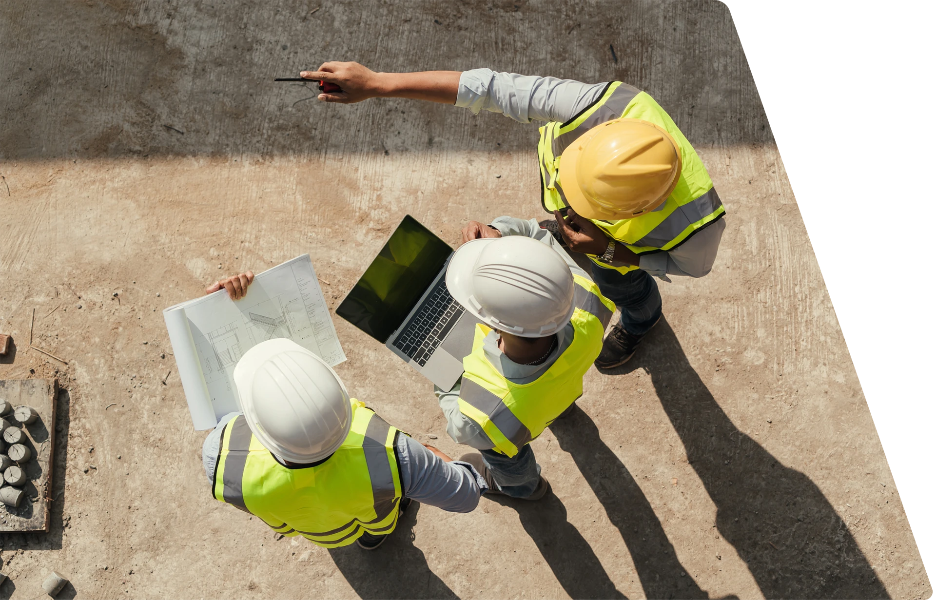 Three construction workers wearing safety vests and helmets are standing on a site. One holds blueprints, another uses a laptop, and the third is pointing, possibly giving directions or discussing plans. | GenFlex